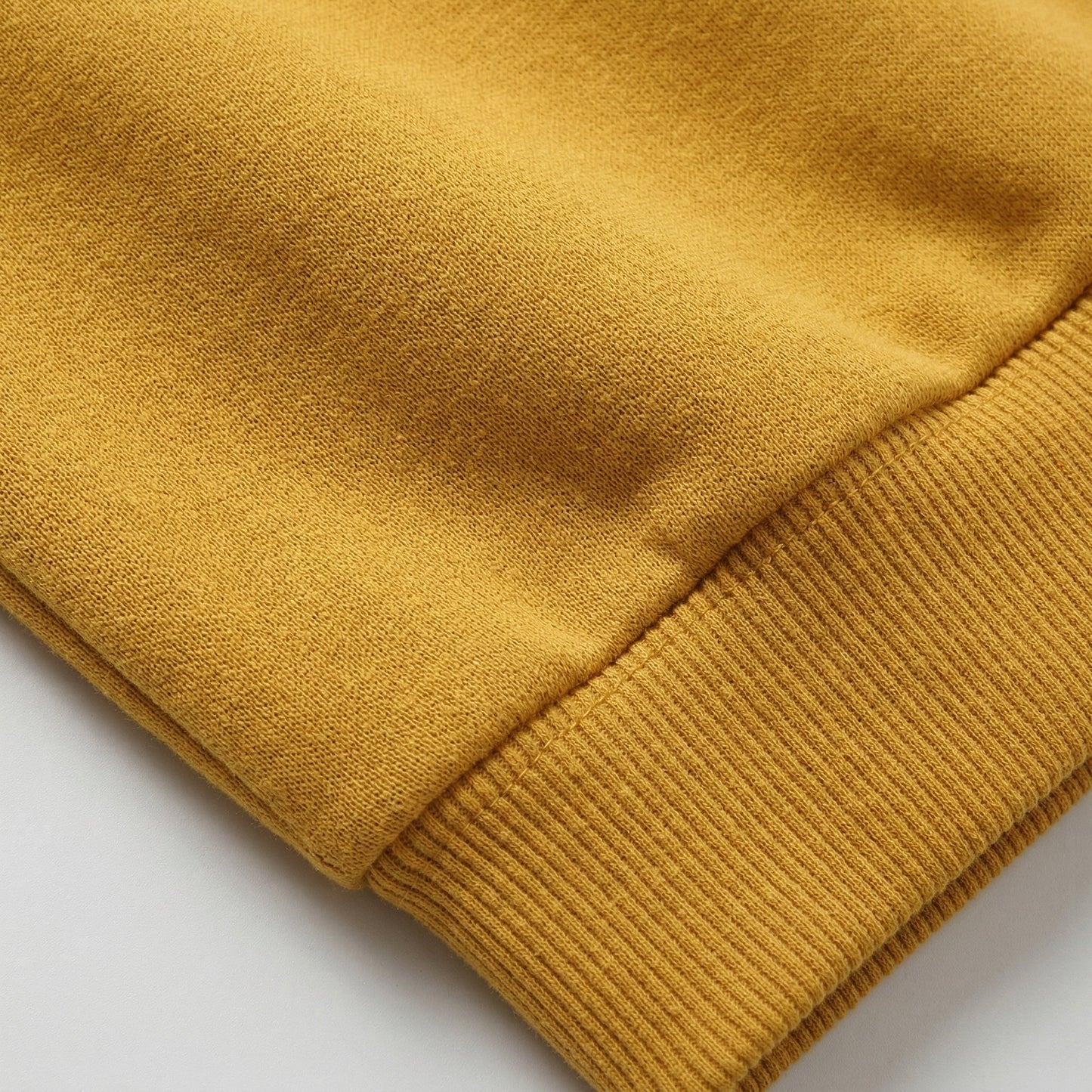 Senfgelber Pullover mit geripptem Ärmelbündchen aus weichem Baumwollstoff, Nahaufnahme