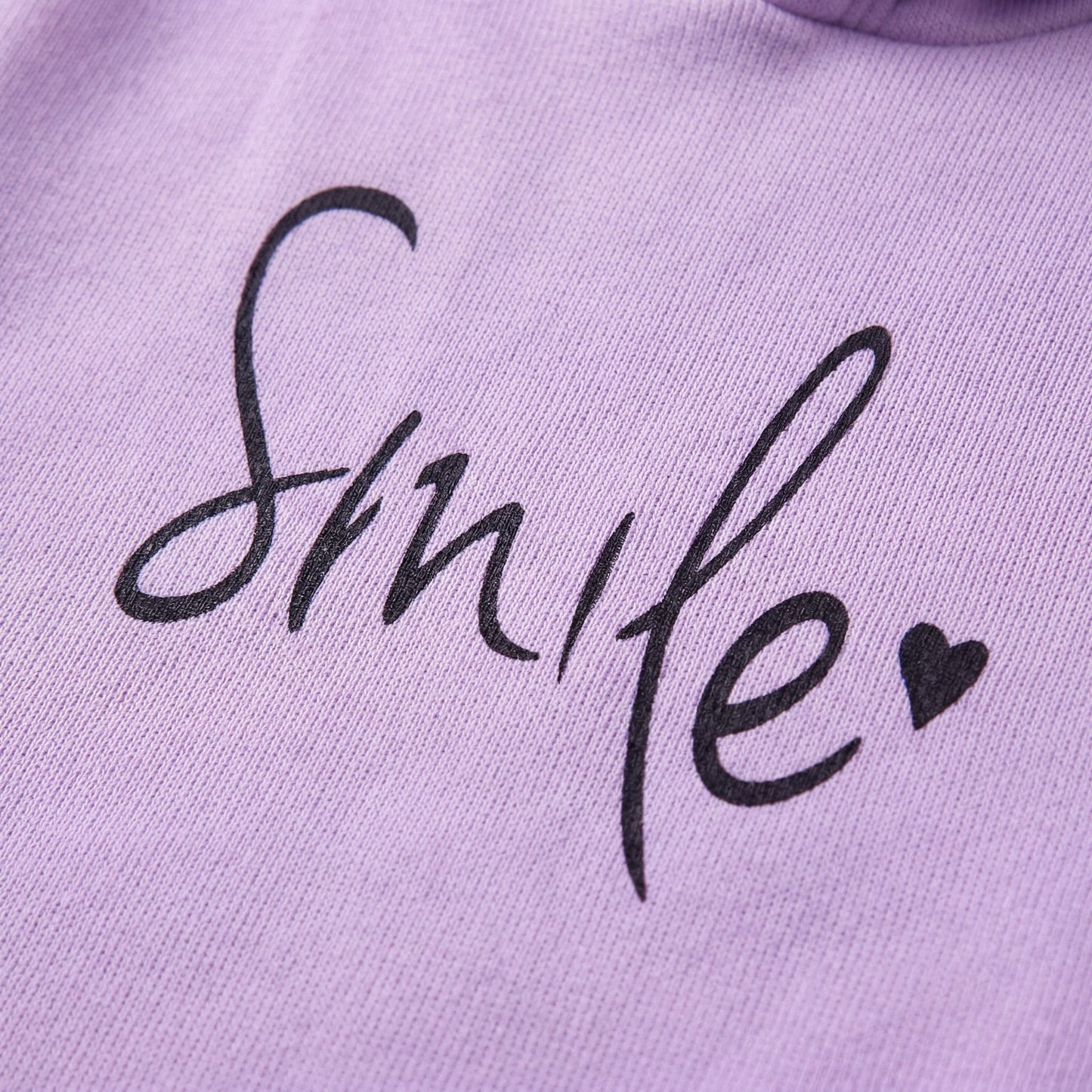 Lila Pullover mit schwarzem handschriftlichem Smile-Schriftzug und Herz-Detail, Nahaufnahme