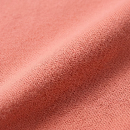 Nahaufnahme eines korallfarbenen, feinen Strickstoffs mit weicher, glatter Textur