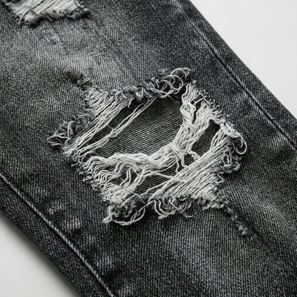 Dunkelgraue Damenjeans mit großen ausgefransten Löchern und Tassel-Details nahaufnahme