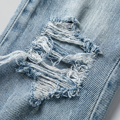 Hellblaue Jeans mit ausgefransten, modischen Rissen und sichtbarer Denim-Struktur Nahaufnahme