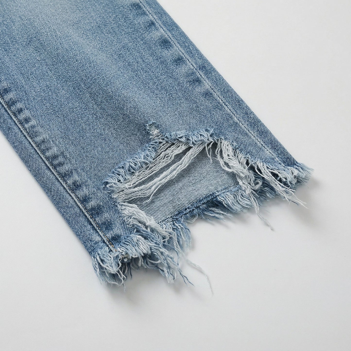 Hellblaue Damenjeans aus Denim mit ausgefranstem, zerstörtem Saum und geradem Schnitt, Nahaufnahme