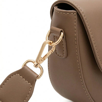 Nahaufnahme goldfarbener Karabiner und breitem Taupe PU-Leder Schulterriemen an runder Tasche