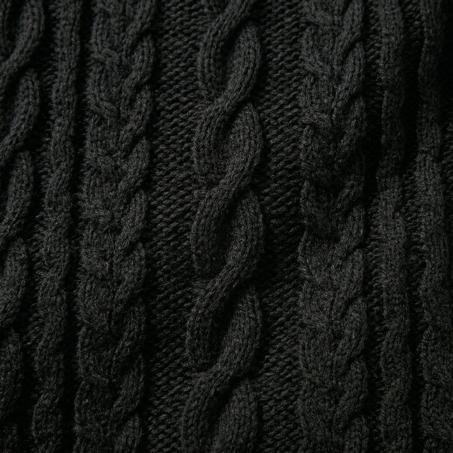 Nahaufnahme dunkelgrauer grob gestrickter Pullover mit markantem Zopfmuster