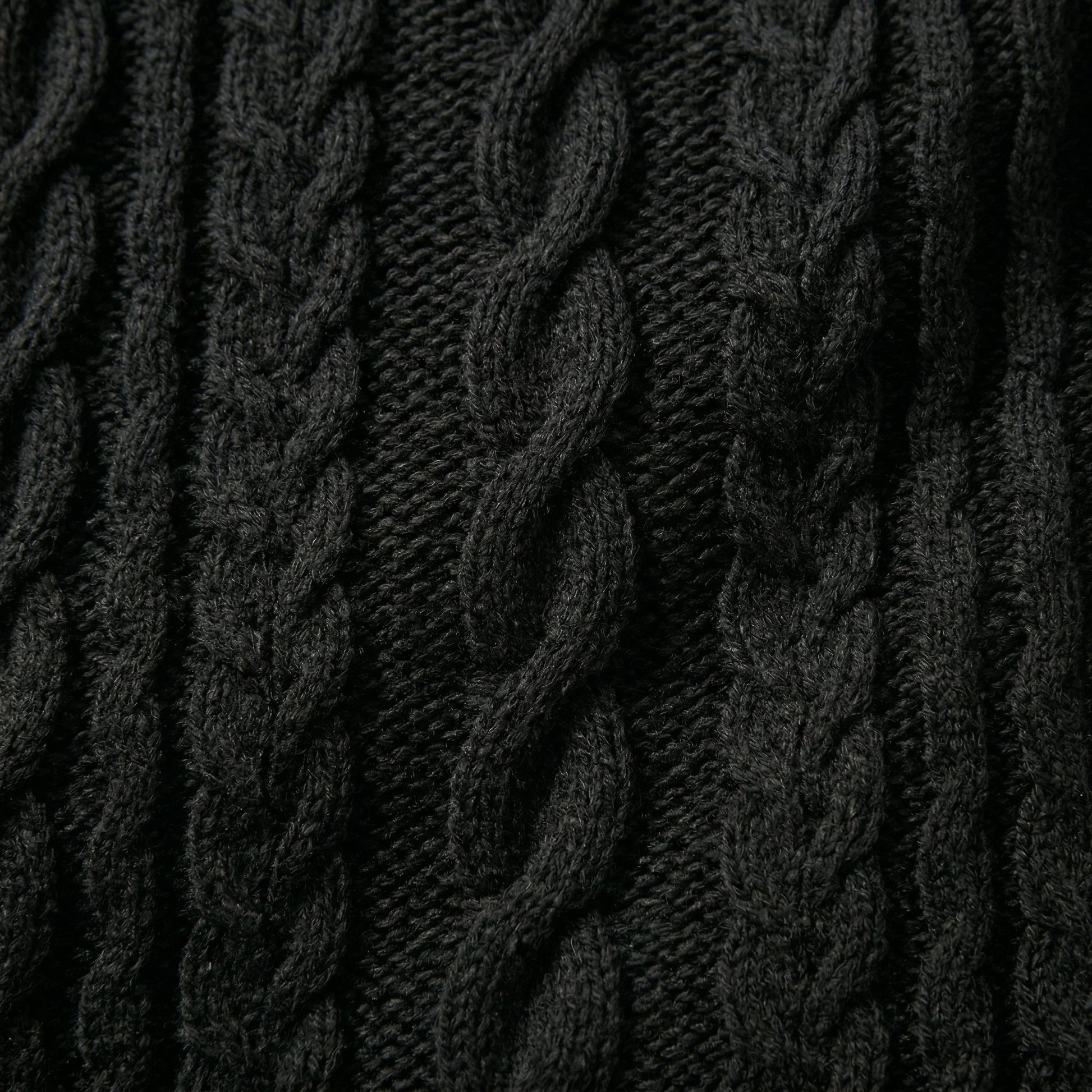 Nahaufnahme dunkelgrauer grob gestrickter Pullover mit markantem Zopfmuster