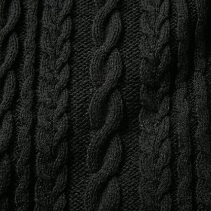 Nahaufnahme dunkelgrauer grob gestrickter Pullover mit markantem Zopfmuster