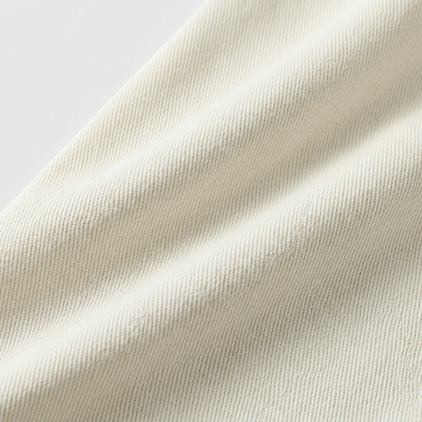 Nahaufnahme cremeweißer Baumwollstoff mit diagonaler Twill-Webstruktur und feiner Drapierung