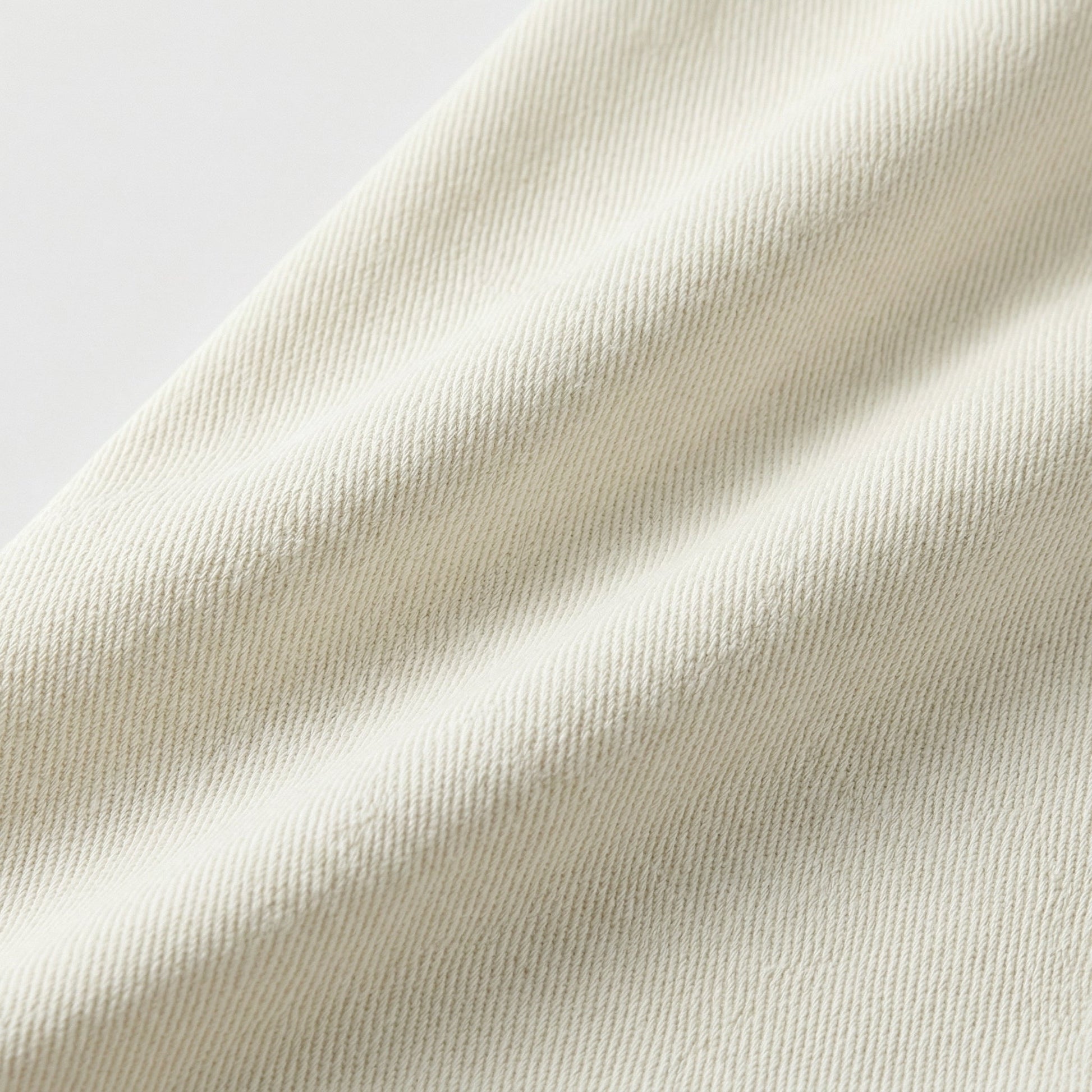 Nahaufnahme cremeweißer Baumwollstoff mit diagonaler Twill-Webstruktur und feiner Drapierung