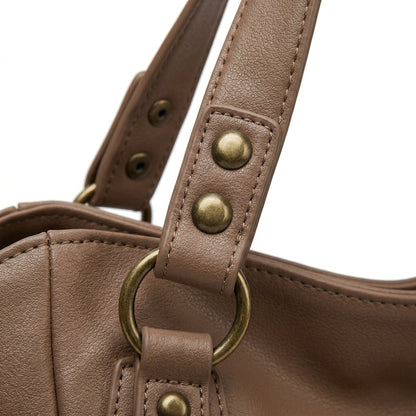 Nahaufnahme braune Hobo-Handtasche mit antikgoldfarbenen Nieten und D-Ring am Griff