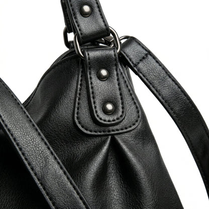 Schwarze Hobo-Handtasche aus weichem Kunstleder mit silbernen Nieten und breiten Tragehenkeln, Detailansicht