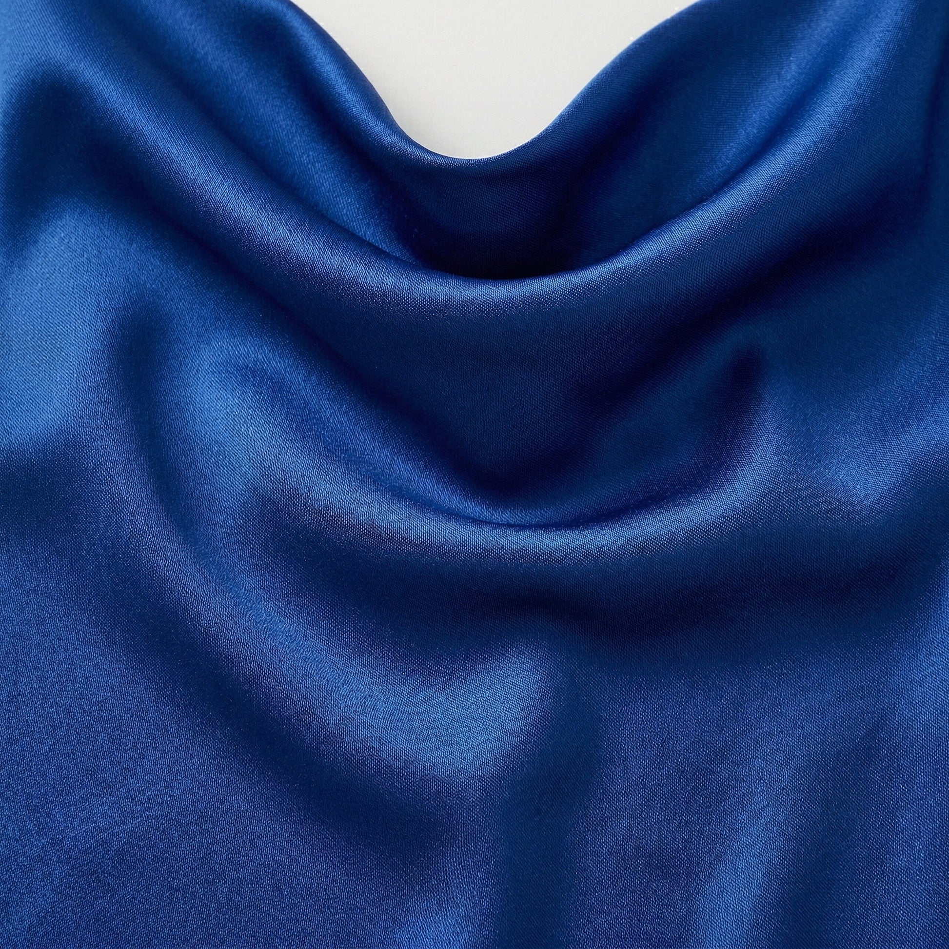 Tiefe königsblaue glänzende Satin-ähnliche Stofftextur mit weichen Falten