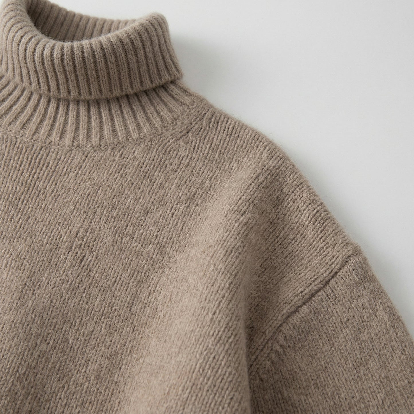 Beiger grob gestrickter Pullover mit Stehkragen und langen Ärmeln, Nahaufnahme Schulter und Kragen
