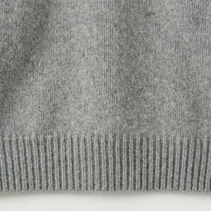 Nahaufnahme hellgrauer Strickpullover mit geripptem Saum und weicher, flauschiger Oberfläche