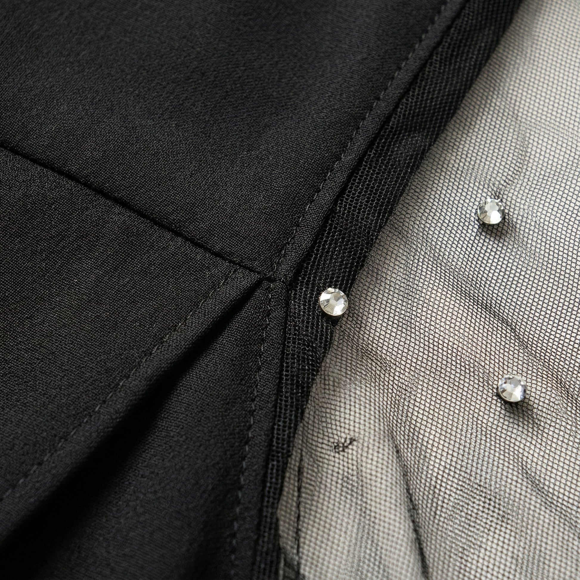 Schwarzes Damenoberteil mit transparentem Mesh-Ärmel und glitzernden Strasssteinen Detailansicht