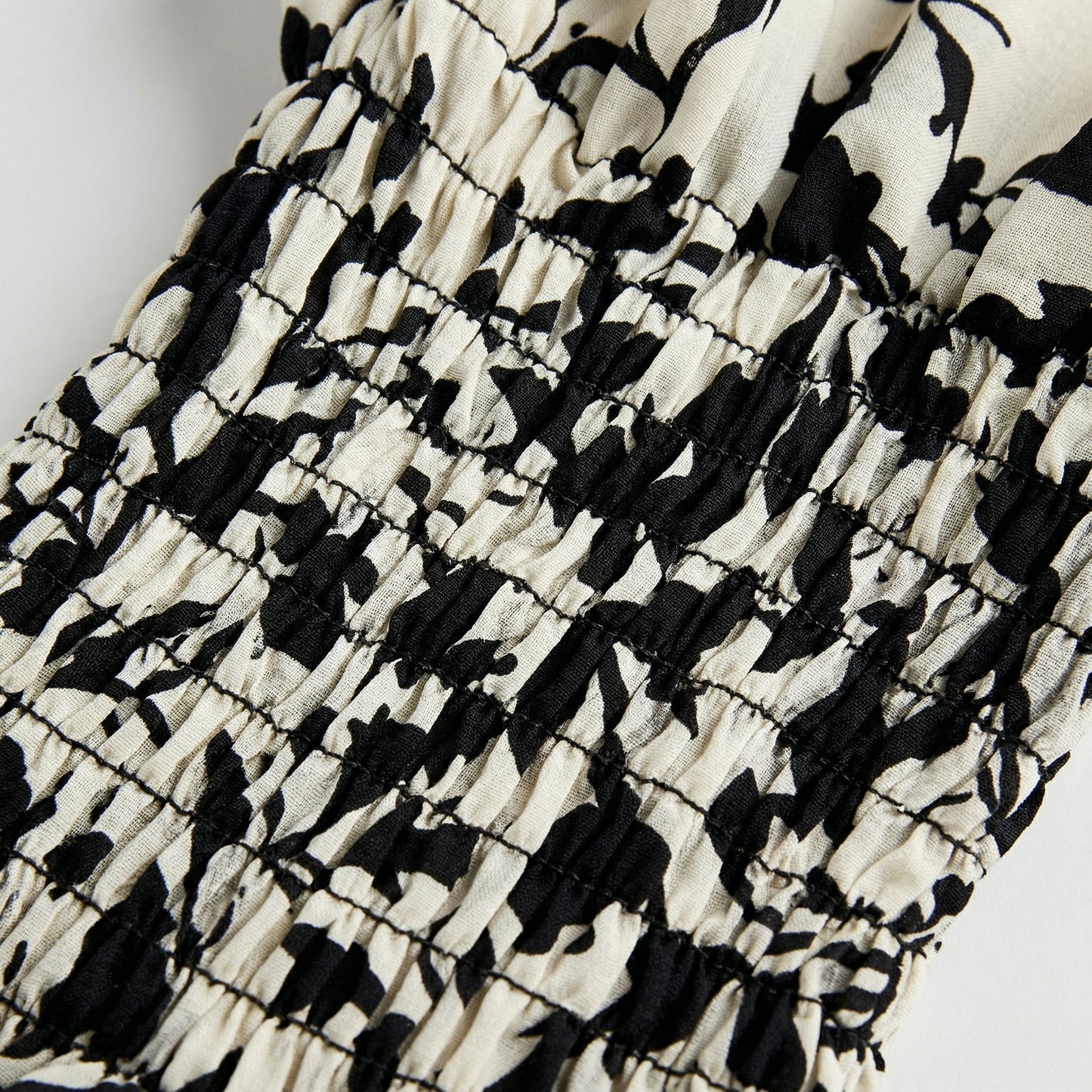 Detailaufnahme smocking elastische Raffung mit schwarz-cremefarbenem abstraktem Muster auf Bluse