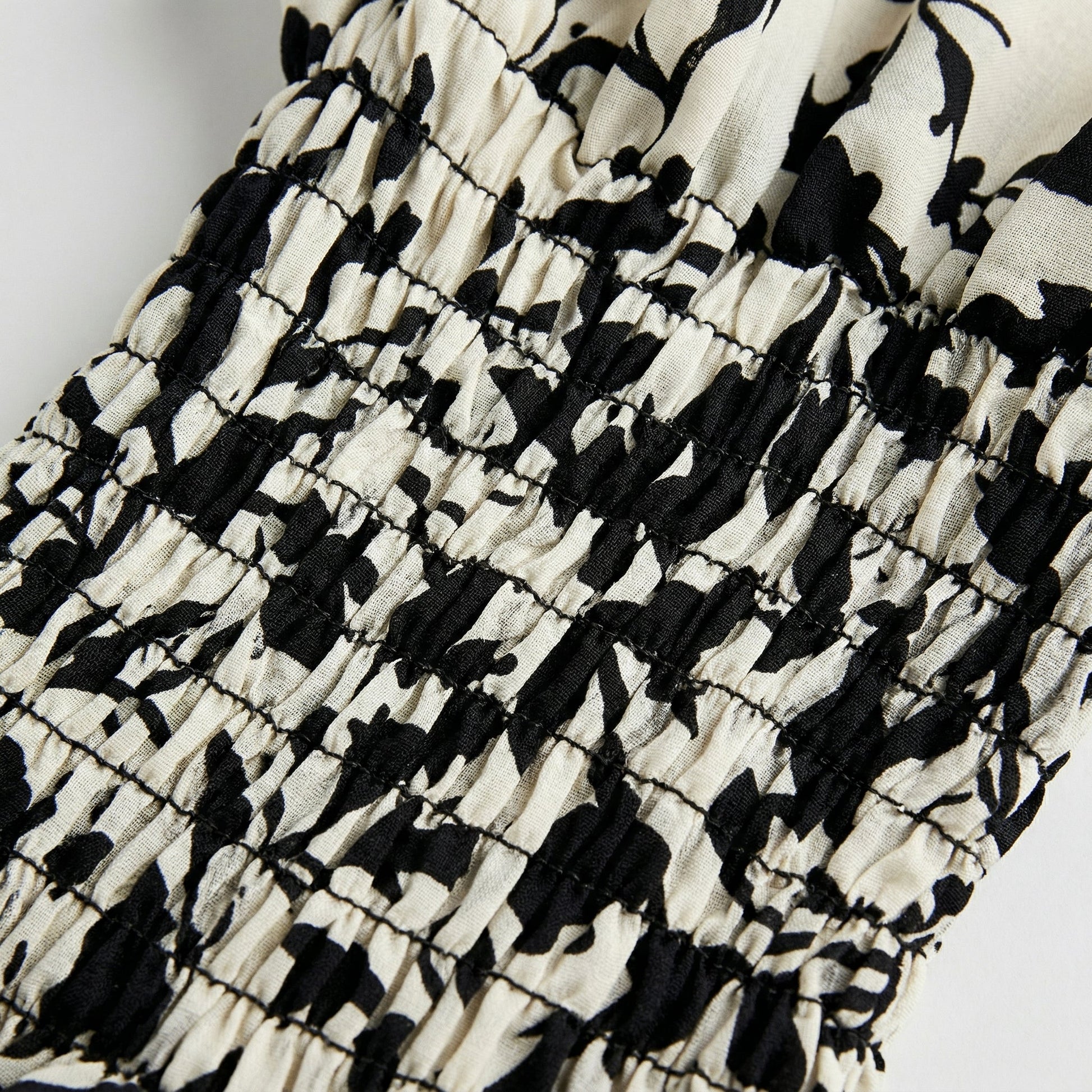 Detailaufnahme smocking elastische Raffung mit schwarz-cremefarbenem abstraktem Muster auf Bluse
