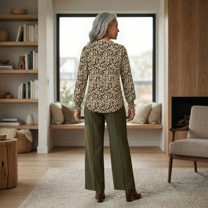 Rückansicht beige Bluse mit schwarzem Blumenmuster und langen Puffärmeln, getragen mit grüner Hose