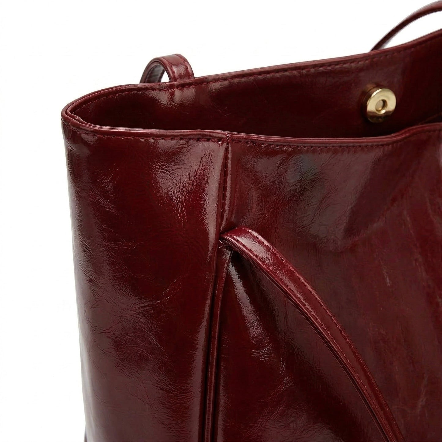 Nahaufnahme weinrote glänzende Ledertasche mit Magnetverschluss und Ledergriff