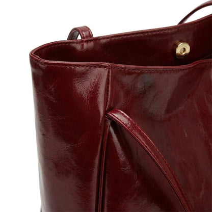 Nahaufnahme weinrote glänzende Ledertasche mit Magnetverschluss und Ledergriff