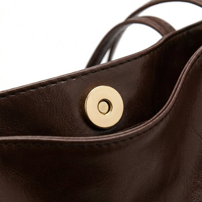 Dunkelbraune Ledertasche mit goldfarbenem Magnetverschluss, Nahaufnahme