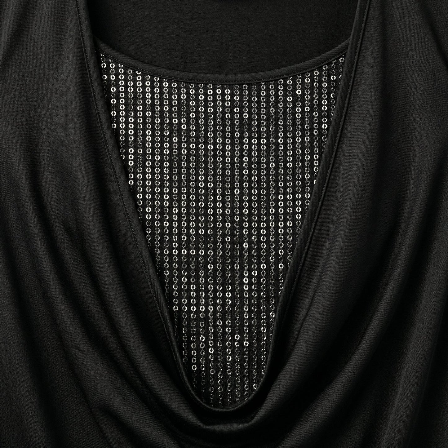 Schwarzes Langarmshirt mit weitem Ausschnitt und silbernen Perlen- oder Paillettenbesatz im Brustbereich