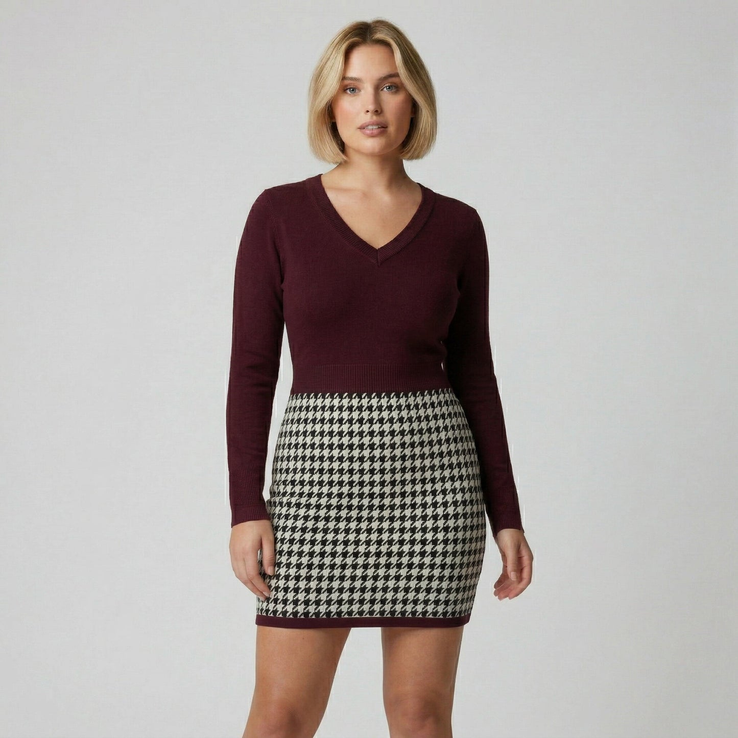 Figurbetontes Strickkleid mit weinrotem V-Ausschnitt-Oberteil und Hahnentrittmuster-Rock, frontale Ansicht
