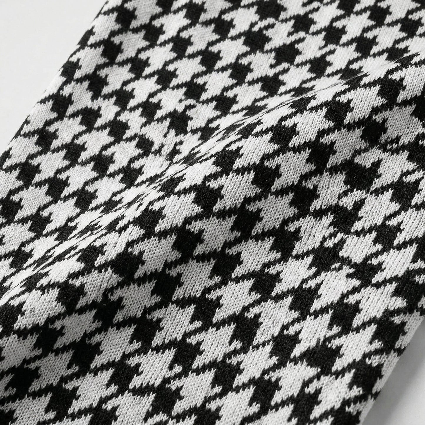 Schwarz-weißes Hahnentrittmuster auf gestricktem Stoff, Nahaufnahme der Textur
