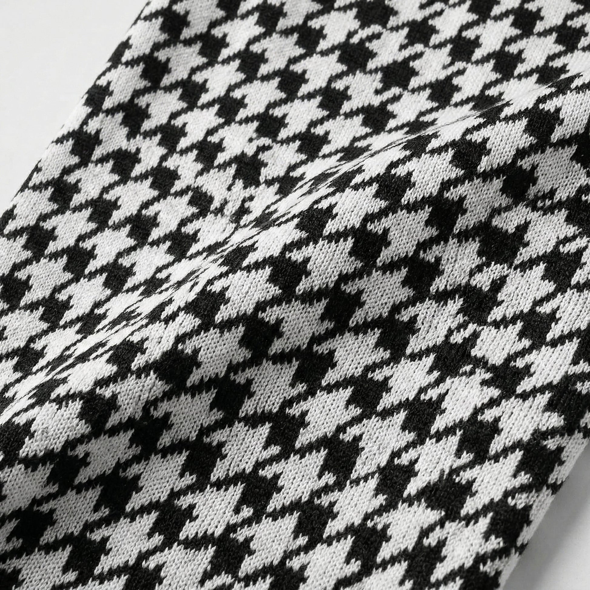 Schwarz-weißes Hahnentrittmuster auf gestricktem Stoff, Nahaufnahme der Textur