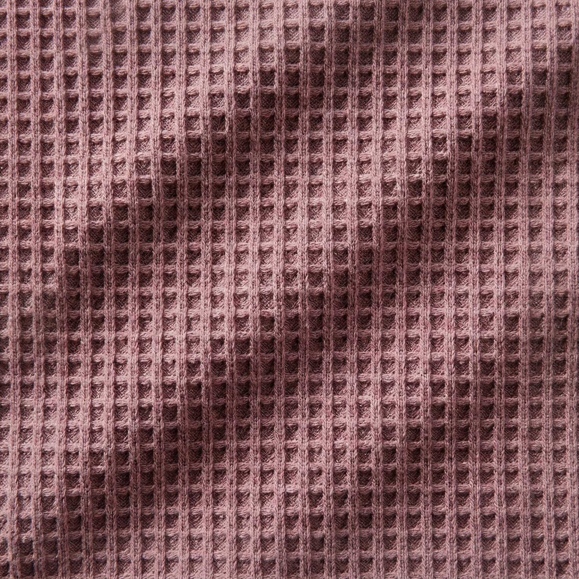 Nahaufnahme eines staubig rosafarbenen Waffelstrickstoffs mit strukturierter Oberfläche