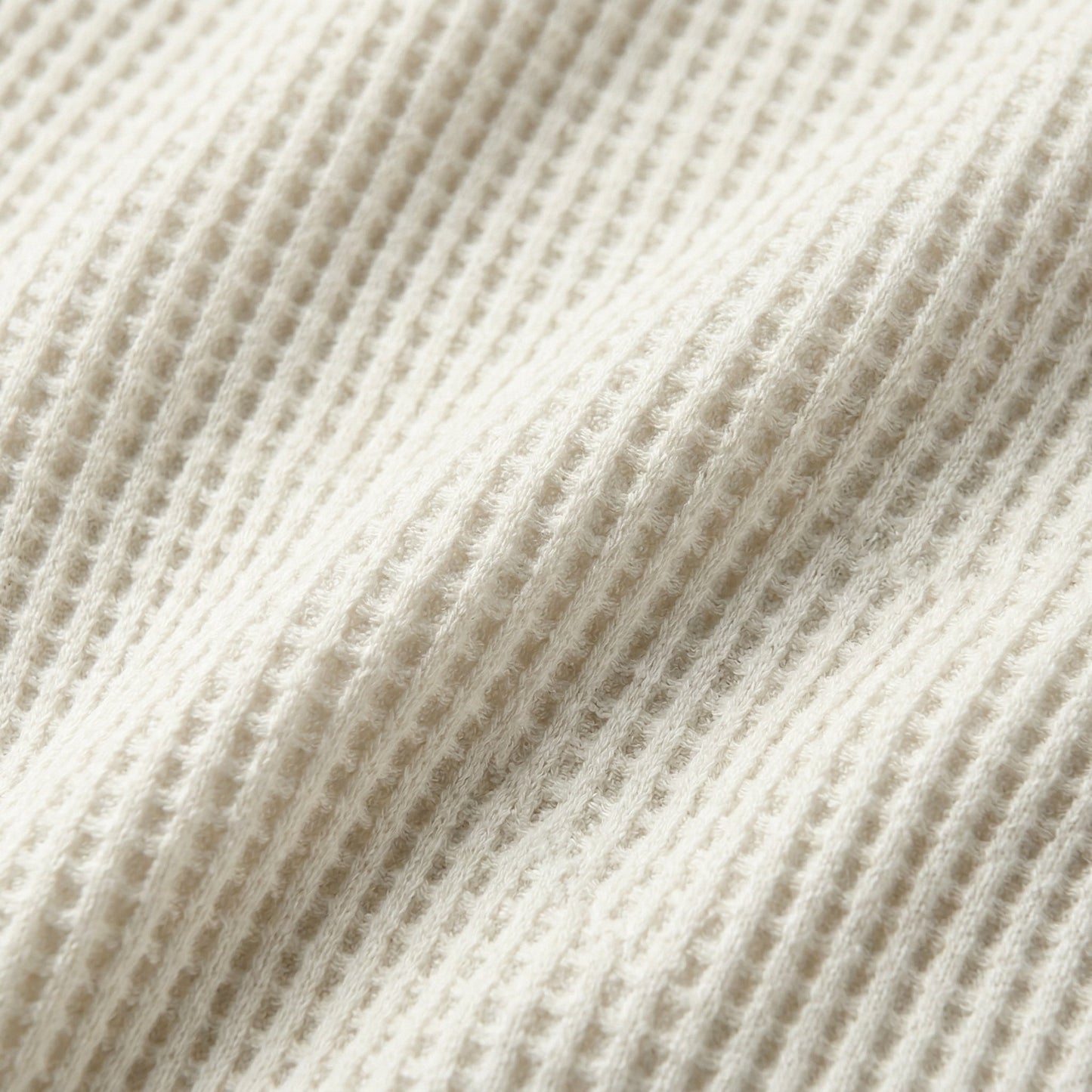 Cremefarbener, gerippter Waffelstrickstoff mit weicher, flauschiger Textur Nahaufnahme
