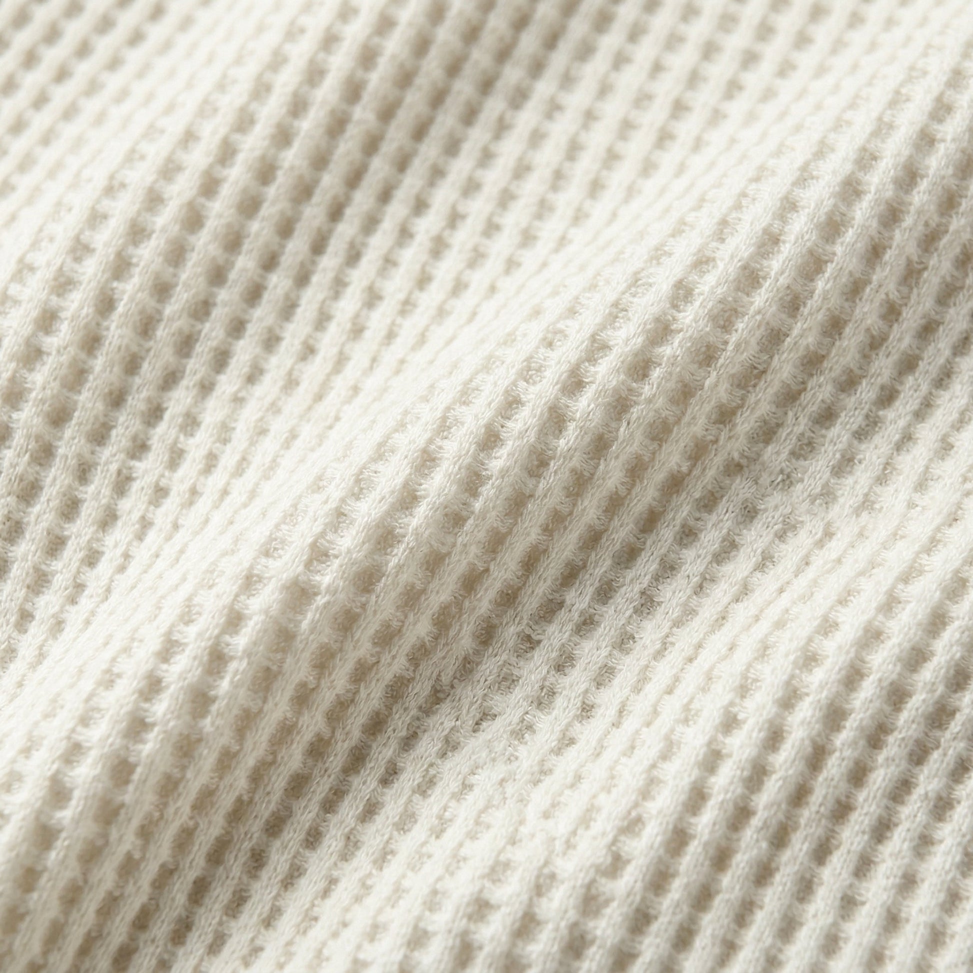 Cremefarbener, gerippter Waffelstrickstoff mit weicher, flauschiger Textur Nahaufnahme