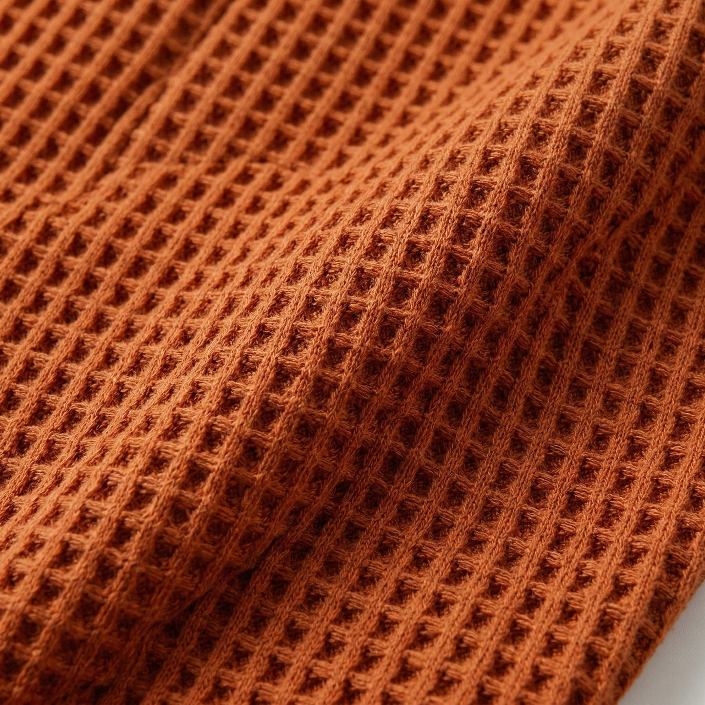 Nahaufnahme rostbraunes waffelgestricktes Stoffmaterial mit strukturierter Oberfläche
